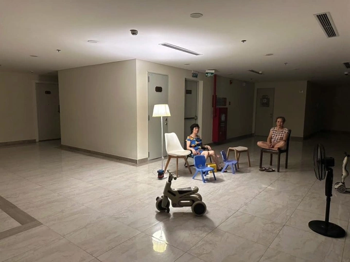 Cư dân tại một chung cư ở Tây Hồ, Hà Nội mang đèn và quạt tích điện ra sảnh chung ngồi hóng mát, sau khi cả tòa nhà gặp sự cố điện, tối 4/8. Ảnh: R.S.T.H