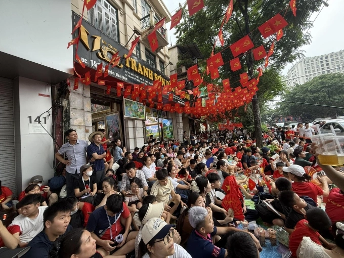 Hàng trăm người dân ngồi trước vỉa hè và trong cửa hàng tranh của anh Cao Văn Quân trên đường Nguyễn Thái Học, chiều 21/8 để xem diễu binh. Ảnh: Khánh Tùng