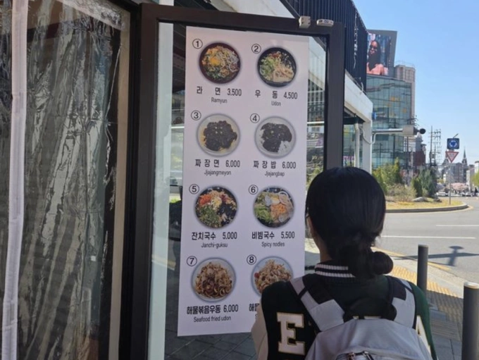 Một sinh viên đại học xem thực đơn bên ngoài nhà hàng ở quận Seodaemun, Seoul, Hàn Quốc, ngày 7/4. Ảnh: Korea Times
