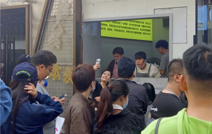 Bai Xianying (mặc áo sơ mi trắng và tạp dề xám) chụp ảnh với một khách hàng tại cửa hàng mới khai trương của mình ở Thiên Tân, tháng 10/2024. Ảnh: VCG