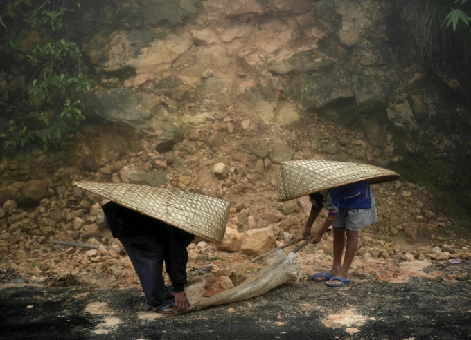 Những người lao động mặc quần ống rộng, đội knup che mưa, dọn dẹp đá lở sau một đêm mưa lớn ở làng Mawsynram năm 2014. Ảnh: Amos Chapple/The Atlantic
