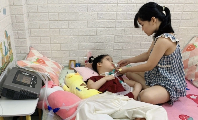 Chị Quyên chăm sóc con gái Vy Anh tại nhà trọ ở quận 12, TP HCM đầu tháng 5/2026. Ảnh: Tường Vy