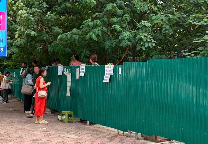 Một số người bán hàng đưa đồ ăn cho khách qua hàng rào tôn trên vỉa hè phố Nguyễn Quốc Trị, phường Yên Hòa, Hà Nội, sáng 13/5. Ảnh: Đ.H